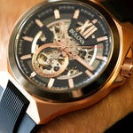 Load image into Gallery viewer, Bulova automatic men's watch with stainless steel case and black leather strap on a display stand.